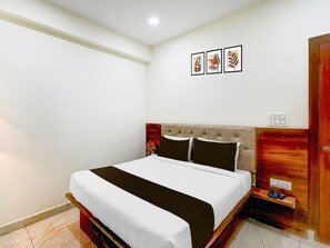 Ein Schlafzimmer mit einem Bett, einem Nachttisch, einem Holzschrank und drei an der Wand befestigten Bildern.