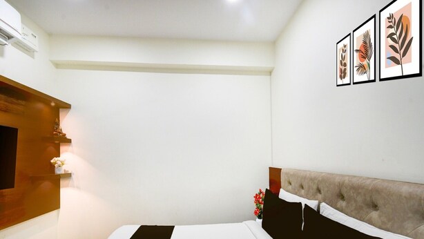 A bedroom with a bed, a wooden cabinet, a wall-mounted TV, and framed artwork. - Hotel O Kakatiya Hills Shree Adithya Luxury (Hyderabad)