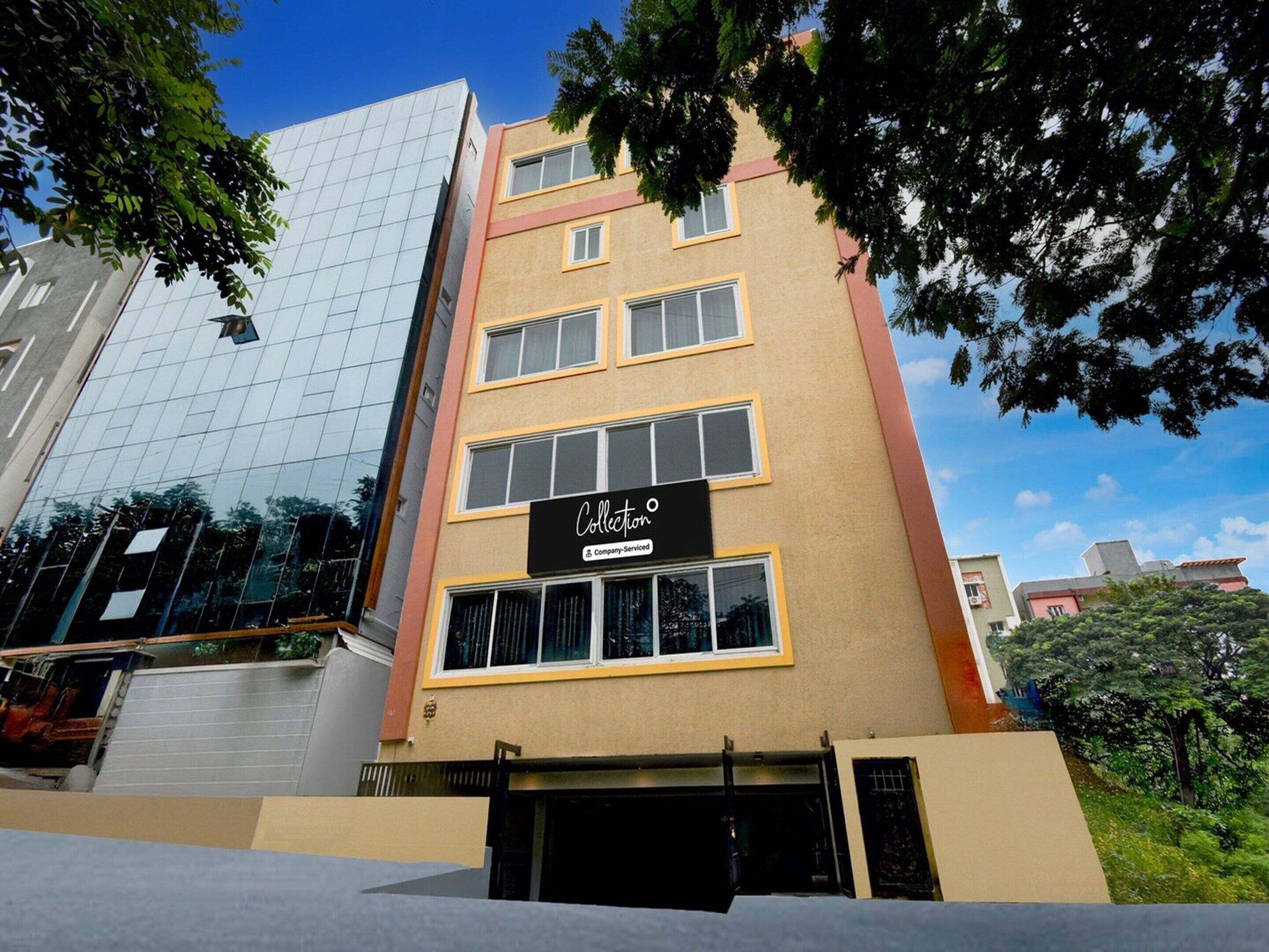 A multi-story building with a modern glass facade and a sign indicating a company-serviced collection.