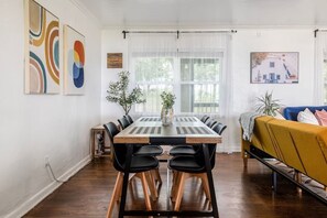 A dining area with a wooden table, black chairs, and a yellow sofa.