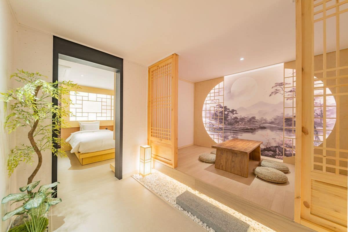 Un dormitorio moderno con una cama, un escritorio de madera y vistas de un paisaje a través de un ventanal circular.