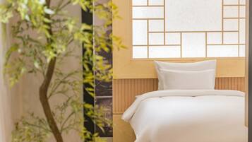 A bedroom with a bed, a window with a geometric pattern, and a plant.