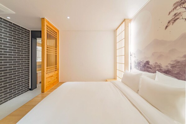 Een slaapkamer met een groot bed, een houten schuifdeur, een bakstenen muur en een muurschildering.