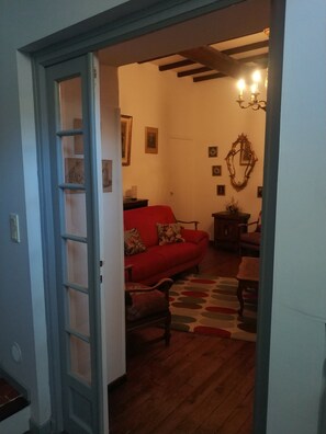 A room with a red sofa, wooden flooring, a patterned rug, and a chandelier. - A 5-minute walk from the historic center, La Maison de Josette (L'Isle-sur-la-Sorgue)