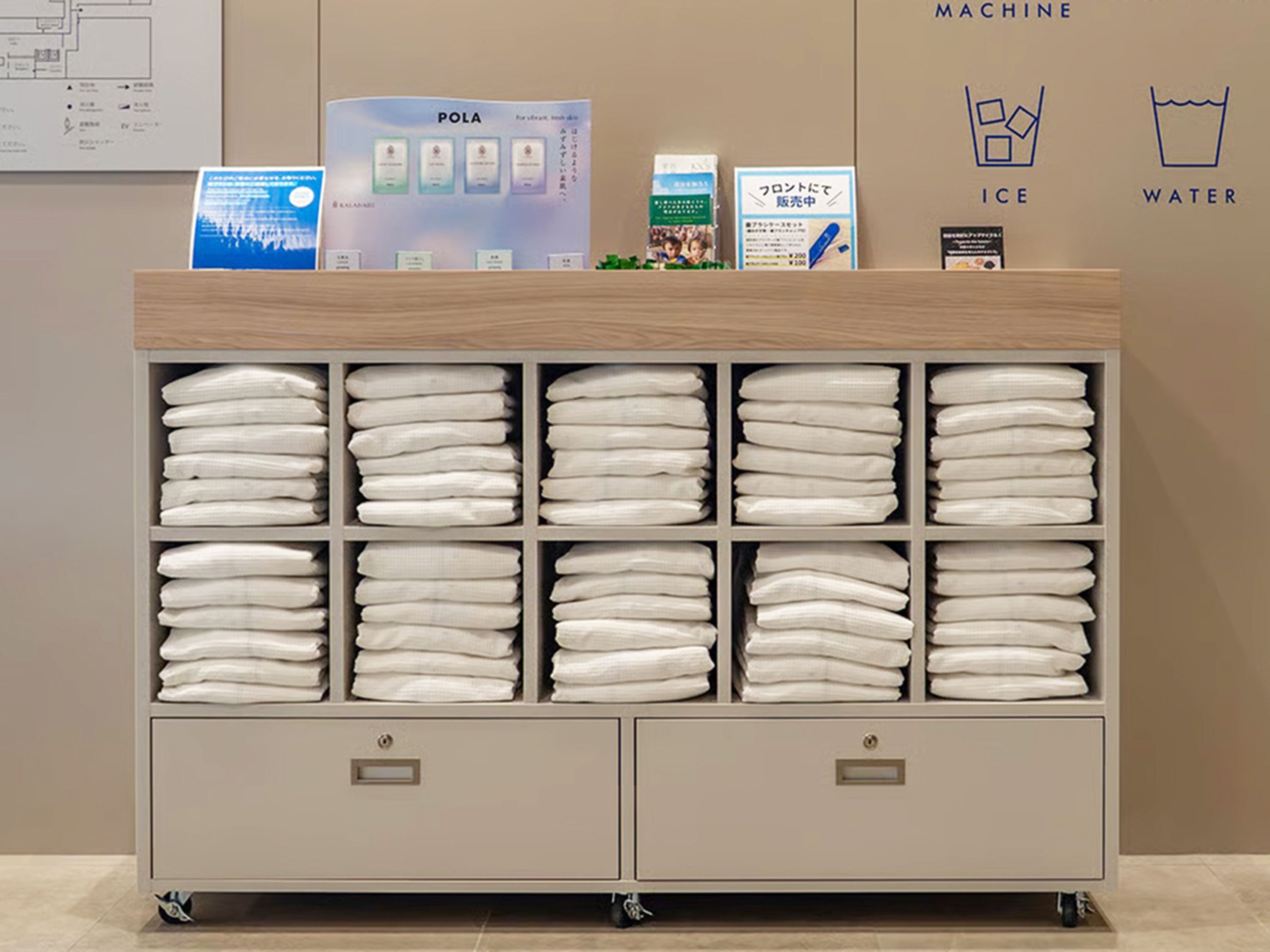 A hotel reception area with a folded towel station, a POLA machine, and ice and water dispensers.