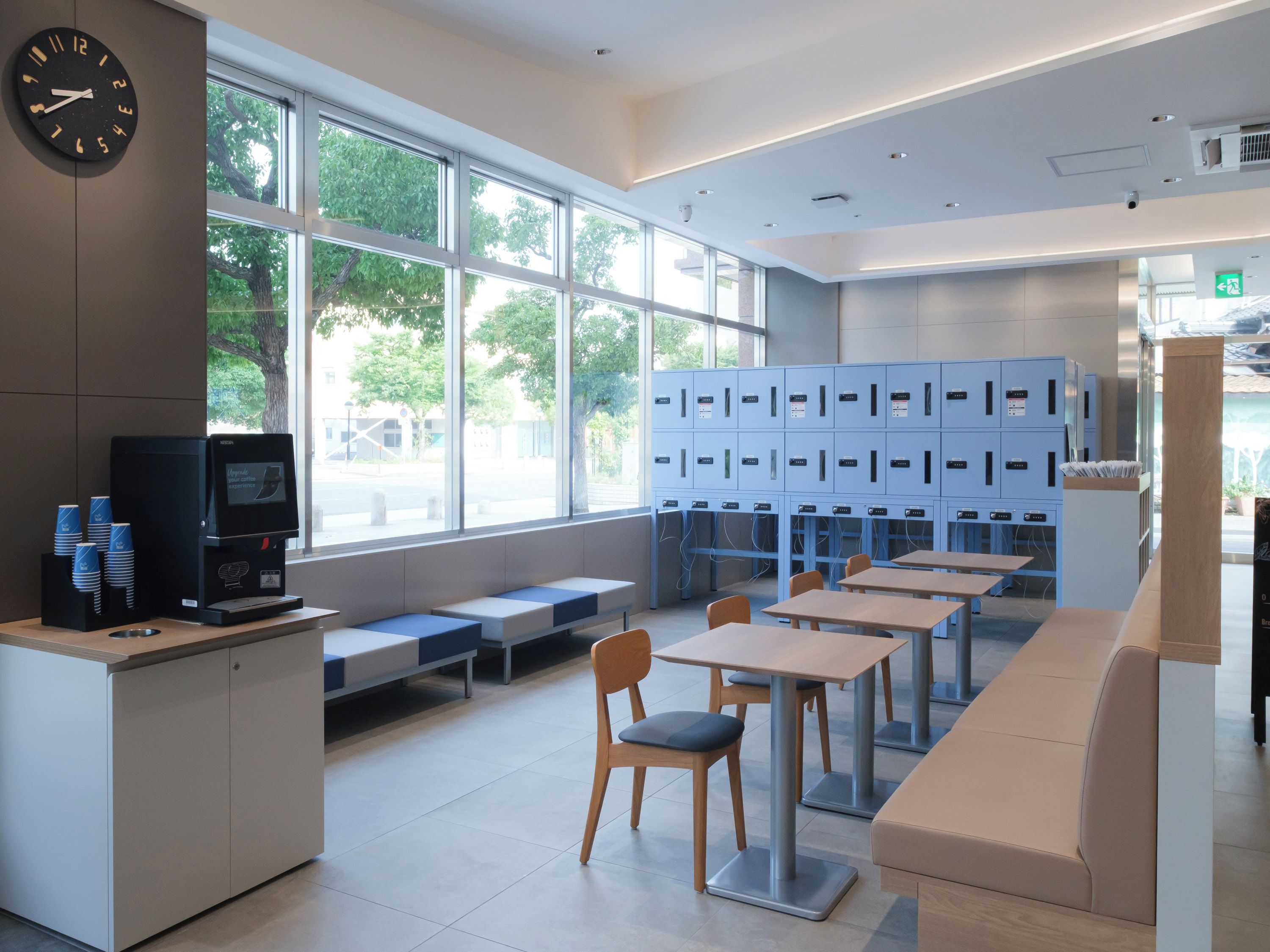 A modern library with a coffee machine, seating area, and blue lockers.