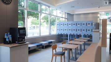A modern library with a coffee machine, seating area, and blue lockers.