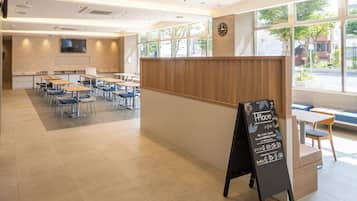 A modern cafe with a wooden counter, tables, and chairs arranged for seating.