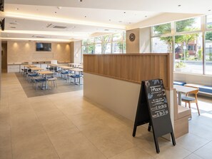 A modern cafe with a wooden counter, tables, and chairs arranged for seating. - Toyoko Inn Ube-Shinkawa-eki (Ube)