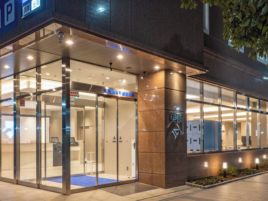 Un bâtiment moderne doté d’une entrée en verre, d’un panneau indiquant clairement la sortie de secours et d’un autre panneau indiquant la présence d’un ascenseur.