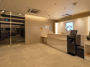 A reception area with a glass door entrance, a reception desk, and a self-service kiosk. - Toyoko Inn Ube-Shinkawa-eki (Ube)