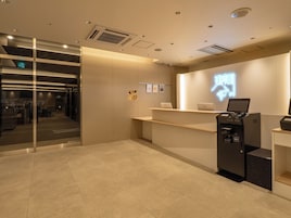 A reception area with a glass door entrance, a reception desk, and a self-service kiosk.