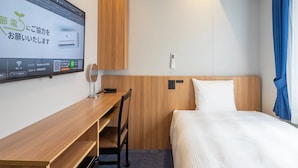 A hotel room with a bed, a desk, a chair, a mirror, a bedside table, and a wall-mounted control panel. - Toyoko Inn Ube-Shinkawa-eki (Ube)