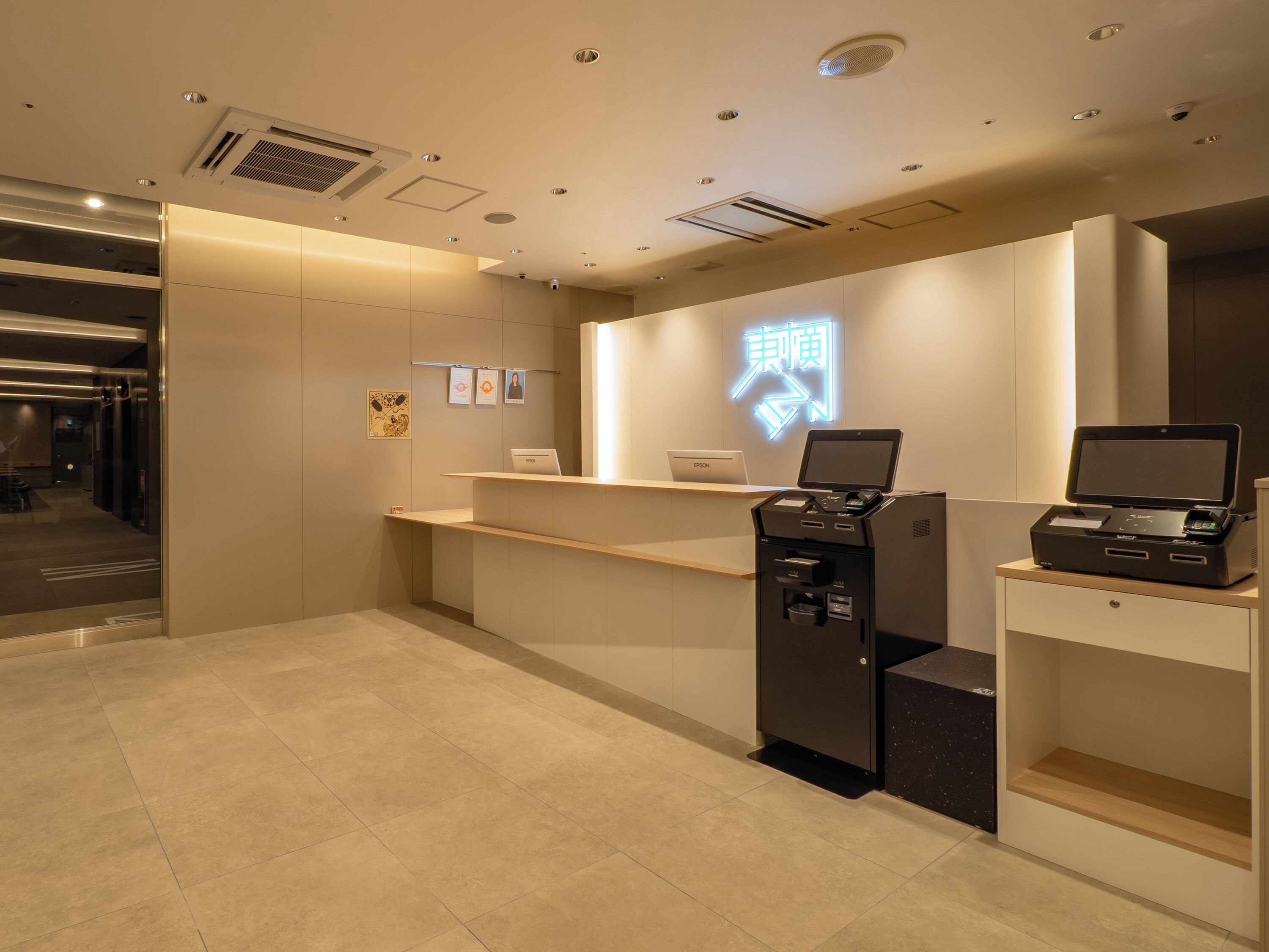 A reception desk with a digital display, a printer, and a laptop.