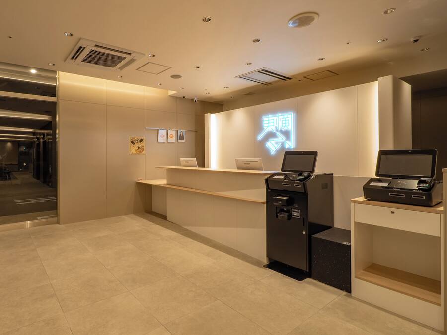 A reception desk with a digital display, a printer, and a laptop.