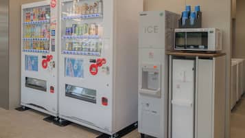 Two beverage vending machines and a microwave oven in a commercial setting.