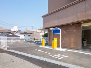 A building with a parking lot, a gated entrance, and a blue awning.
