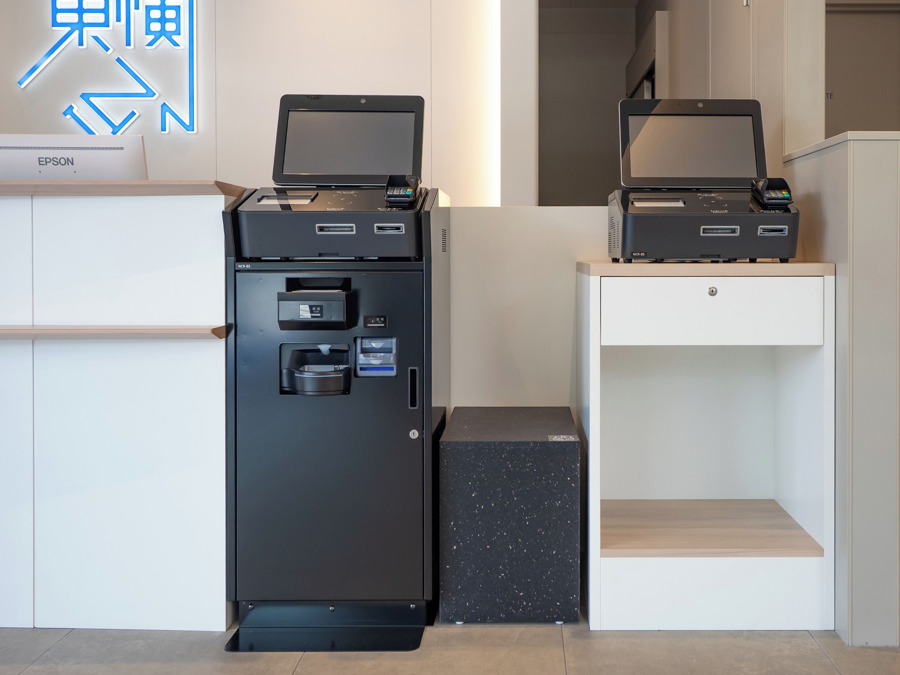 A reception area with a black printer and a white desk.