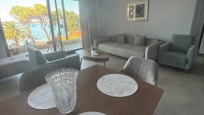 Una sala de estar moderna con comedor, ventanas grandes, un sofá y un cuadro en la pared.