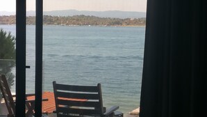 Una habitación con vistas al agua, una silla y una mesa.