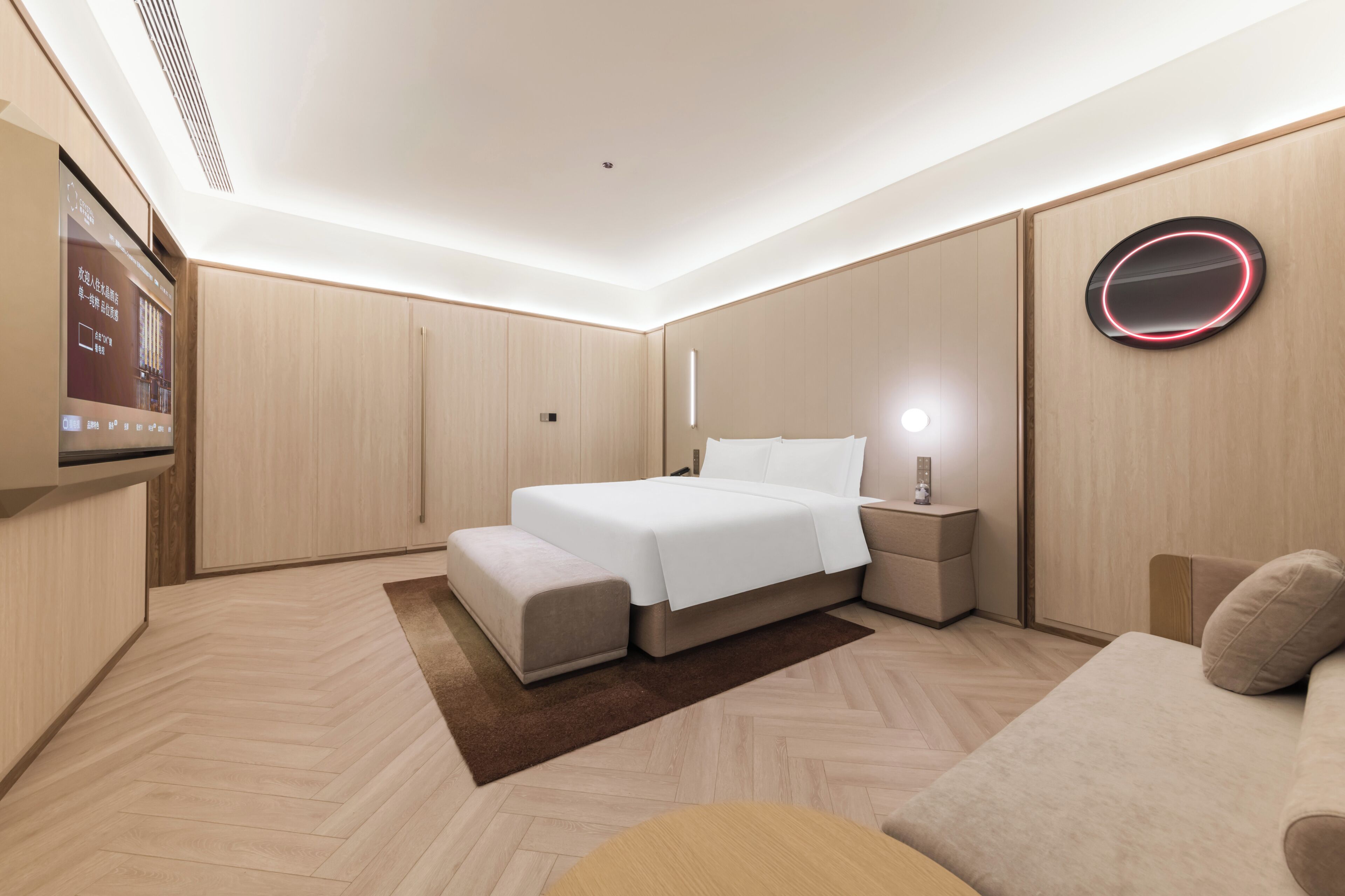 A modern bedroom with a bed, bedside tables, a TV, and a circular light fixture.