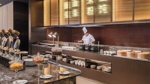 A buffet setup with various food containers, a chef preparing food, and a modern interior design. - Crystal Orange Dongguan Huangjiang (Dongguan)