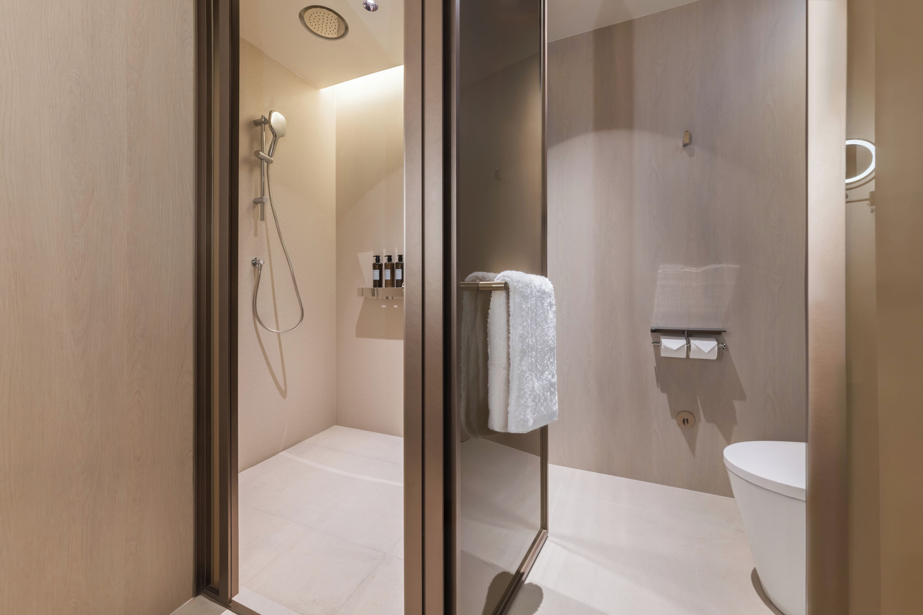 Une salle de bain moderne avec une douche à parois de verre, des toilettes et un porte-serviettes.