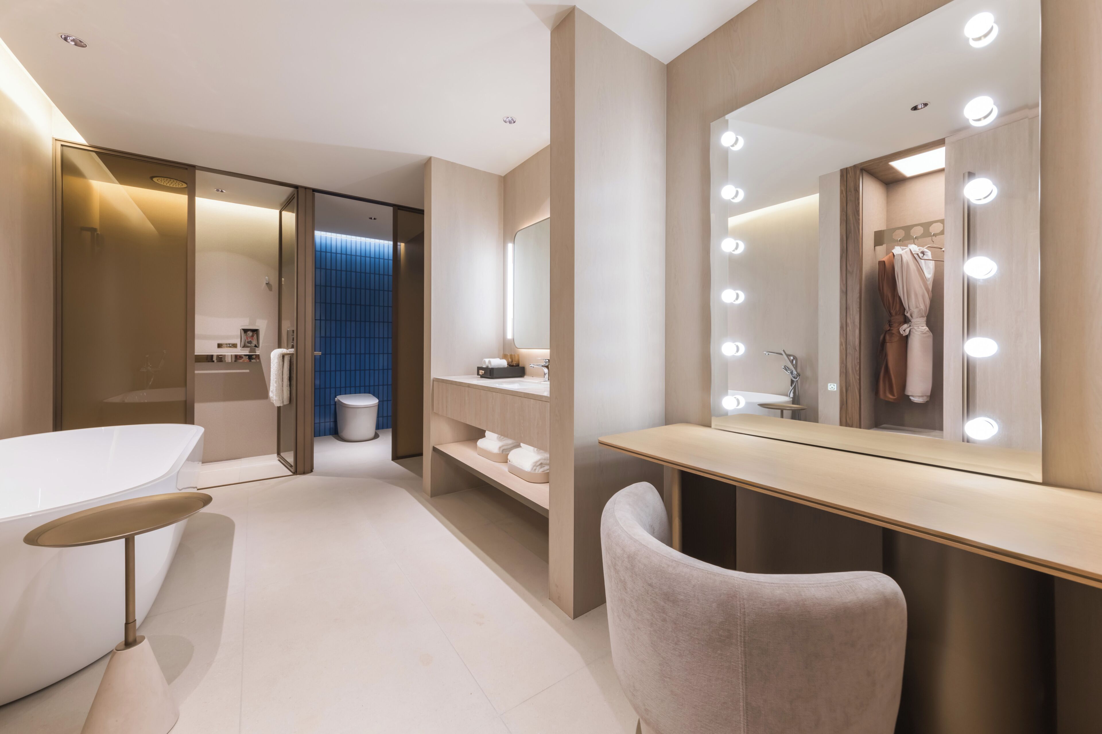 Une salle de bain moderne avec un meuble-lavabo, un miroir avec éclairage intégré et une baignoire.