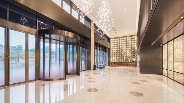 A spacious lobby with a curved glass wall, a seating area, and a patterned wall. - Crystal Orange Dongguan Huangjiang (Dongguan)