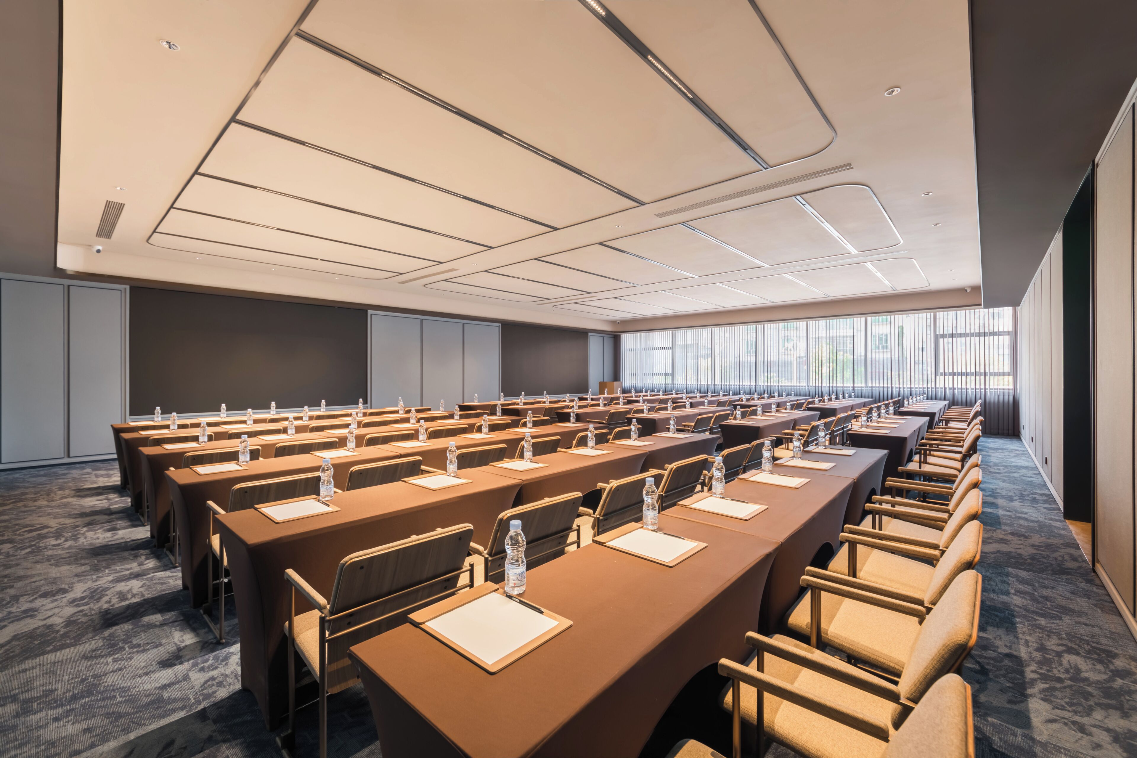 A conference room with multiple tables, chairs, and water bottles.