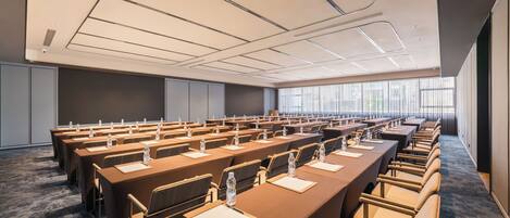 A conference room with multiple tables, chairs, and water bottles.