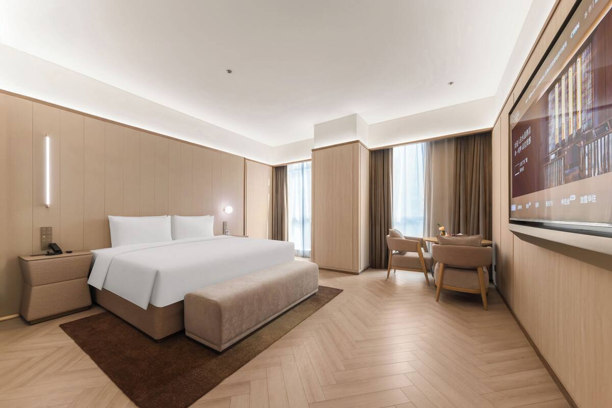 A modern hotel room with a large bed, a desk, and a TV.