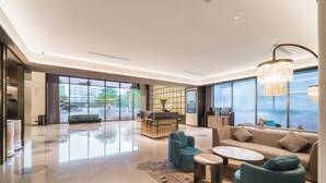 A spacious lobby with a reception desk, seating area, and large windows offering a view of the outdoors. - Crystal Orange Dongguan Huangjiang (Dongguan)