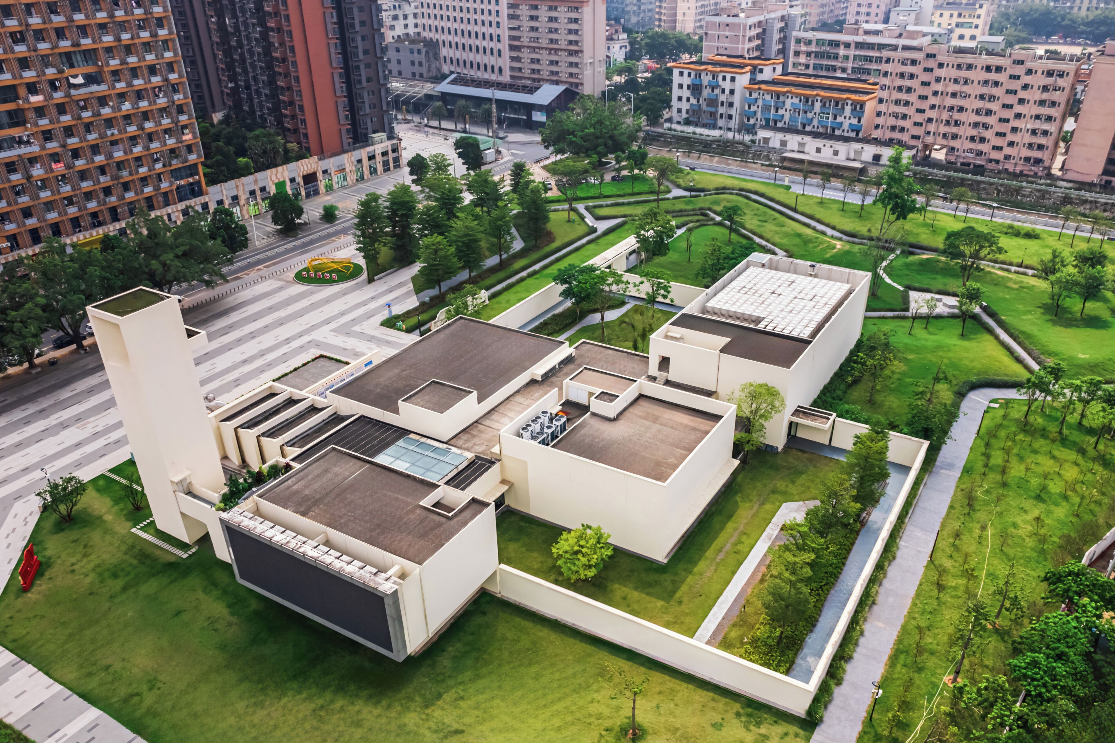A modern building with rooftop terraces, a central courtyard, and surrounding greenery.