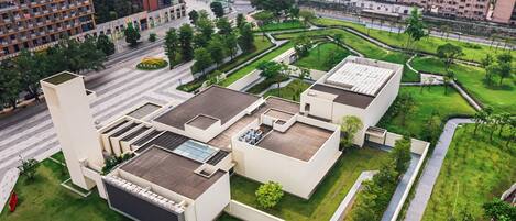 A modern building with rooftop terraces, a central courtyard, and surrounding greenery.