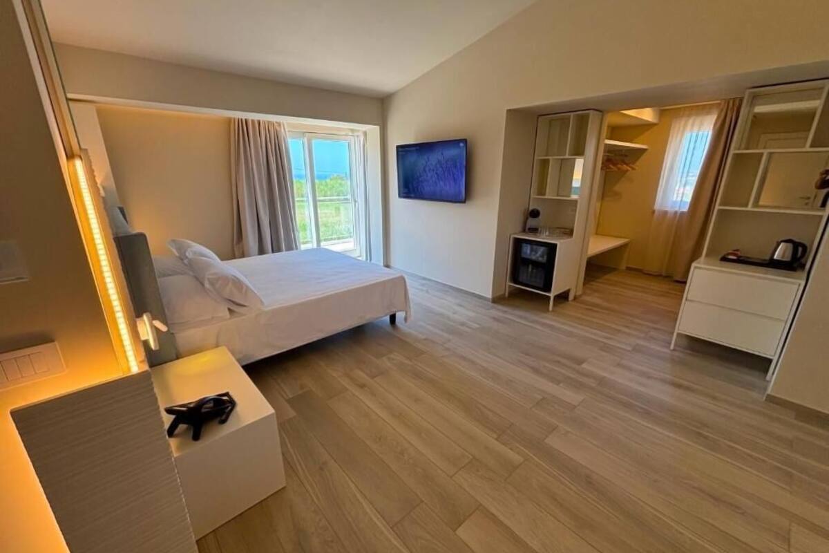 A modern hotel room with a bed, a TV, a desk, and a wardrobe.