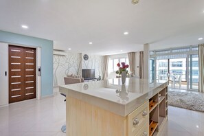 Een moderne woonkamer met een centraal eiland, een eetgedeelte en een groot raam met uitzicht.