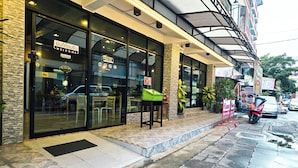 A restaurant with a glass facade, outdoor seating, and a motorcycle parked outside. - Thepmongkol House (Bangkok)