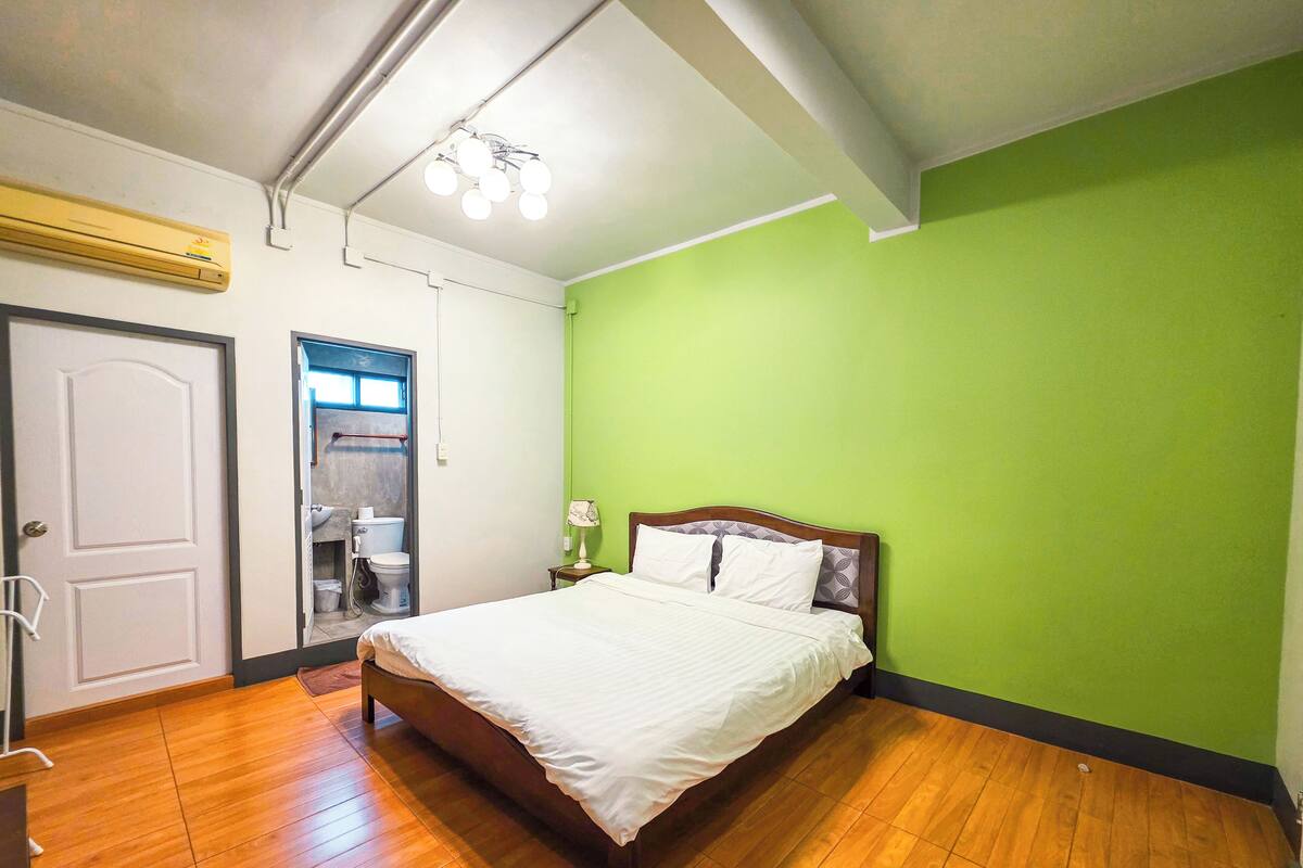 A bedroom with a wooden bed, a green wall, and a white door.