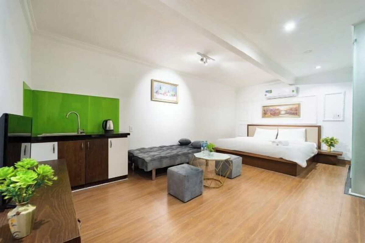 Ein kompaktes Hotelzimmer mit Küchenzeile, einem Bett, einer kleinen Couch und einem runden Tisch.