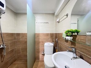 Ein Badezimmer mit Dusche, Toilette, Waschbecken und Spiegel mit Handtuchhalter.