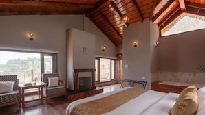 Un dormitorio con una cama grande, una chimenea, un sofá y vistas al exterior.