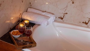 Una bañera con una toalla enrollada, velas y aperitivos en una bandeja.