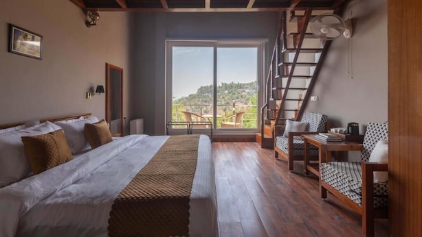 Un dormitorio con una cama grande, una escalera de madera y vistas al exterior.