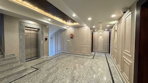 A hallway with a marble floor, a fire extinguisher, and a door with a handle. - EMROZ BY KINGS RESORT (Pahalgam)