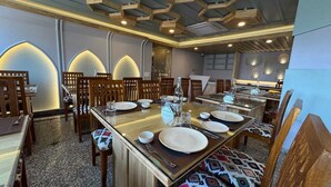 A restaurant with a long wooden table set for dining, surrounded by wooden chairs. - EMROZ BY KINGS RESORT (Pahalgam)
