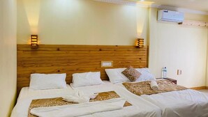 Habitación de hotel con dos camas, cabecero de madera, aire acondicionado instalado en la pared y lámparas de noche.