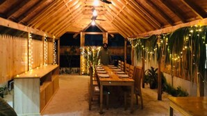 Un comedor interior con una larga mesa de madera, sillas y un ventilador de techo.