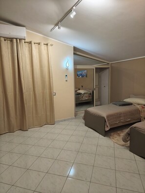 A bedroom with a bed, a nightstand, a wall-mounted light, and a door leading to another room. - Cibali rooms (Catania)