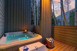 Ein Whirlpool mit Kerze, Bierdose und Handtuch auf einer Holzterrasse.